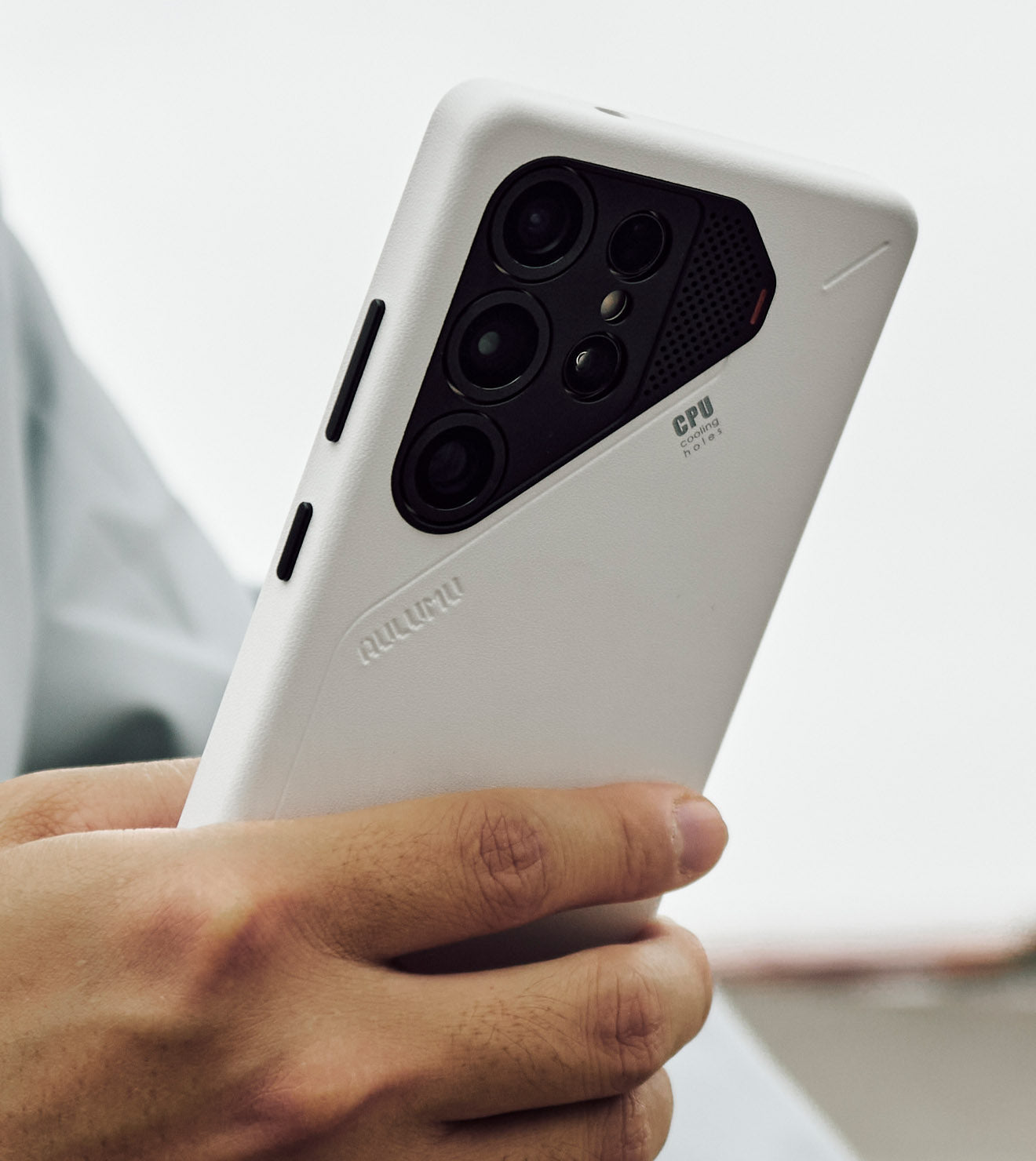Hand holding a Samsung Galaxy S25 Ultra in an AULUMU white PU leather case, showing the raised black camera bezel and slim protective fit.