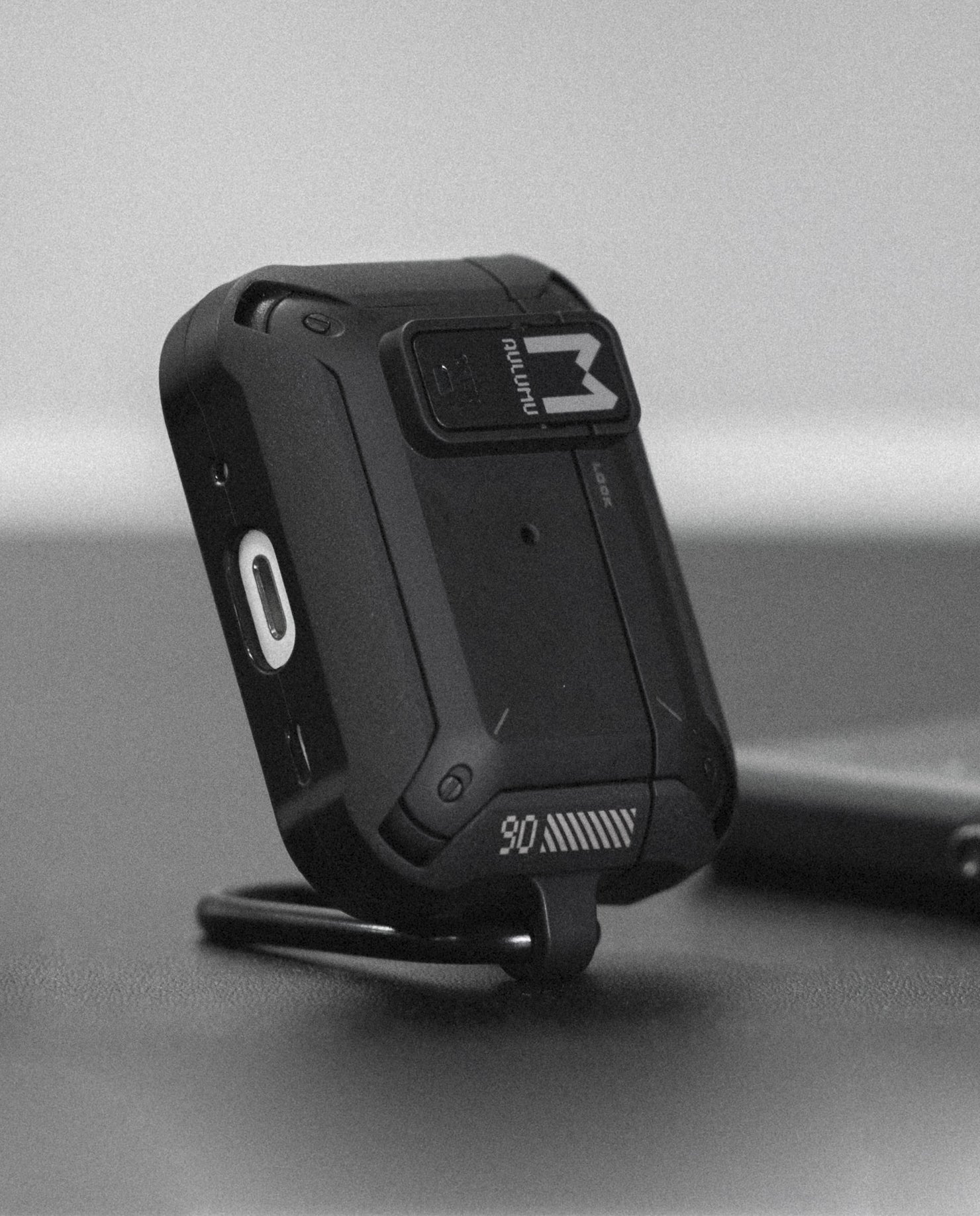 AULUMU A19 AirPods Pro case standing on its metal keychain, showing rugged front panel and lock switch